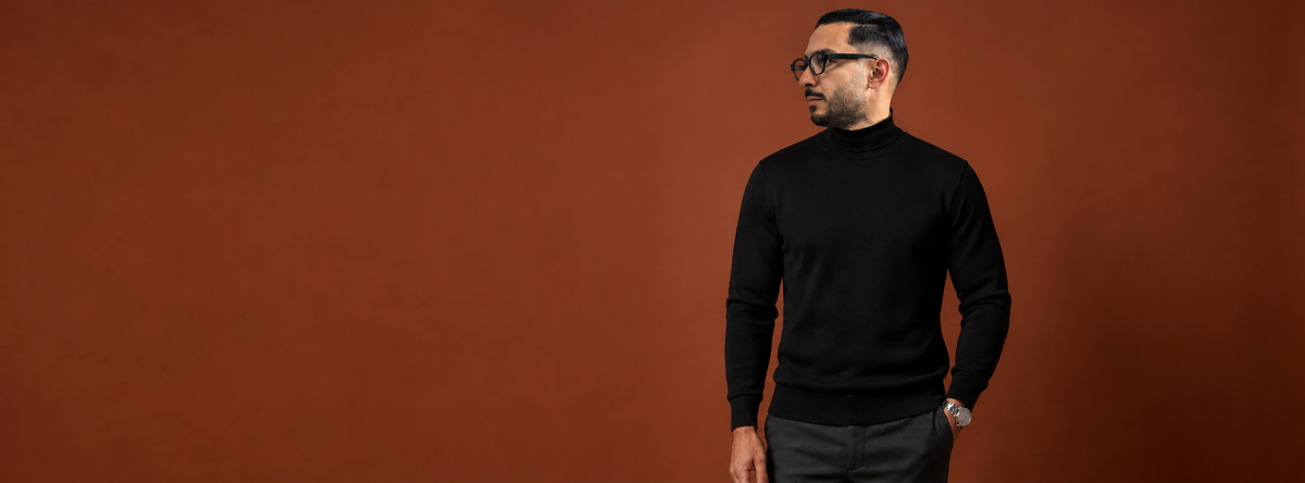 Homme en pull col roulé noir sur fond terracotta